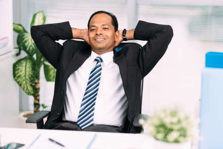 Businessman relaxing at the office with hands behind his headの写真素材
