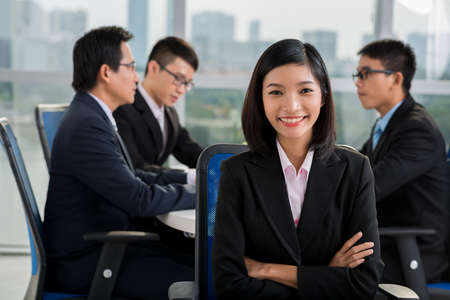 Smiling Vietnamese business lady on the background of her colleagues having a meetingの写真素材