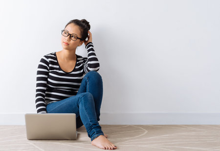 Pensive girl sitting on the floor with a laptop