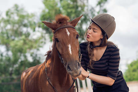 Young girl in jockey cap kissing her horseの写真素材