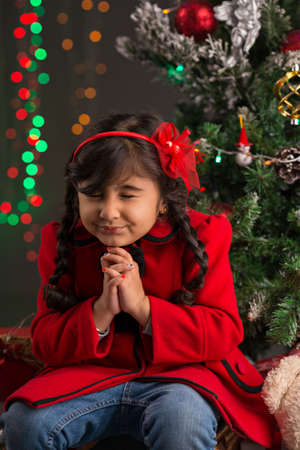 Girl sitting under the Christmas tree and making a wishの写真素材