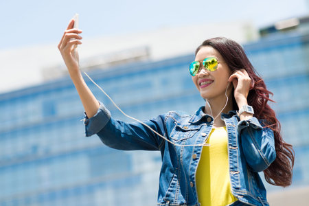 Cheerful girl listening to the music and talking selfie