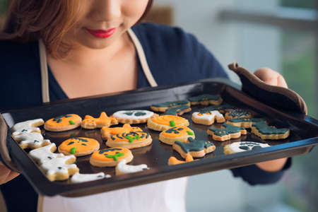 Cropped image of housewife enjoying the smell of Halloween cookies on the trayの写真素材