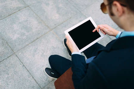 Over the shoulder view of man working on digital tablet, focus on tabletの写真素材
