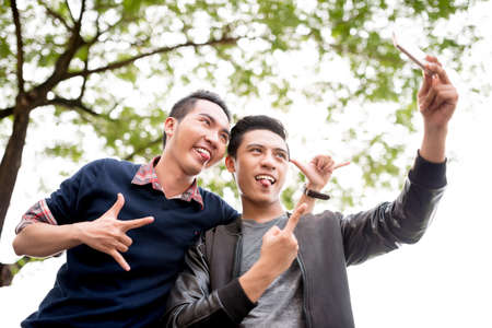 Vietnamese young men pulling out tongues while talking selfieの写真素材