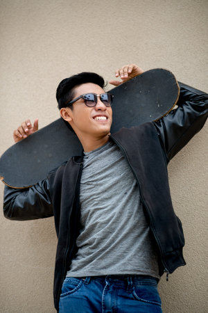 Happy man in sunglasses holding a skateboard: outdoor lifestyle portraitの写真素材
