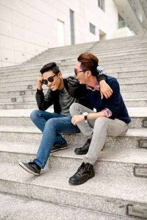 Hugging friends sitting on the steps and laughingの写真素材