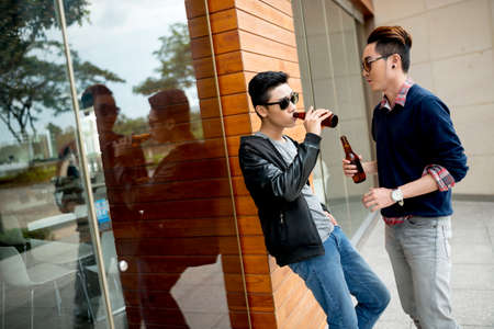 Friends drinking beer and talking outdoorsの写真素材