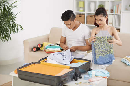 Asian young couple packing suitcase for vacationの写真素材