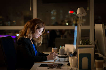 Side view of business lady working in the office late at nightの写真素材
