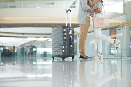 Cropped couple kissing for farewell before plane departureの写真素材