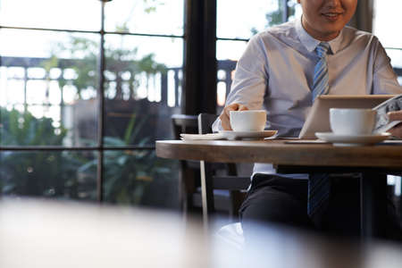Cropped image of entrepreneur having lunch and reading news on digital tabletの写真素材