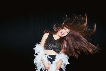Young excited Asian woman dancing in nightclub