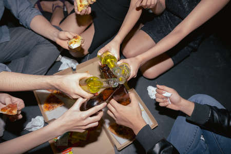 Young people drinking beer and eating pizza at the partyの写真素材
