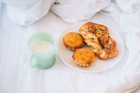 Fresh pastry and a cup of milk on the bedの写真素材