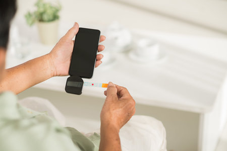 Hands of senior man measuring glucose level at home