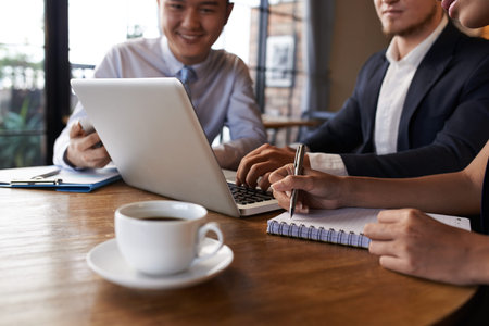 Business people gather at laptop in café, selective focus