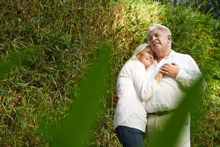 Hugging married mature couple standing in bamboo thicketの写真素材
