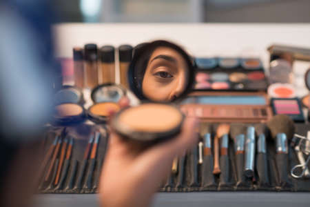 Woman looking in compact mirror before doing make-upの写真素材