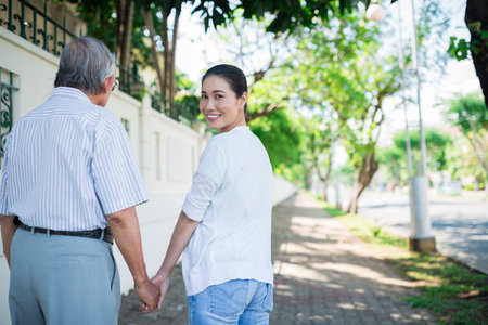 Vietnamese woman walking in the street with her aged fatherの写真素材