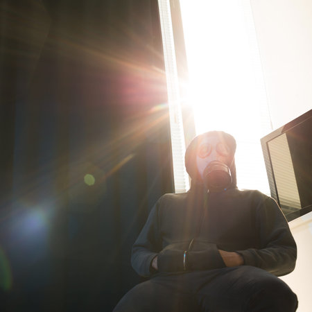 Man in hood and respirator sitting at wallの写真素材