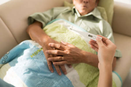 Hand of woman measuring temperature of senior patientの写真素材