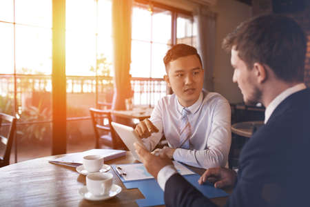 Two businessmen sitting in cafe and discussing business projectの写真素材
