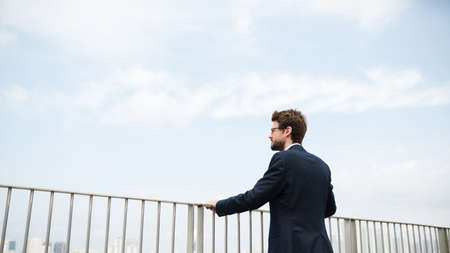 Businessman standing on the rooftop and enjoying city viewの写真素材