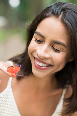 Happy woman looking at butterfly on her handの写真素材