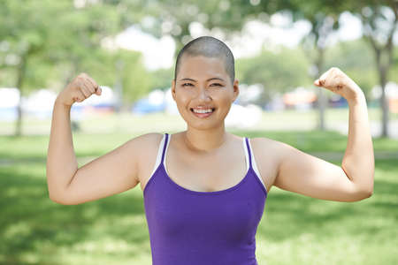 Portrait of sporty Asian woman showing her bicepsの写真素材