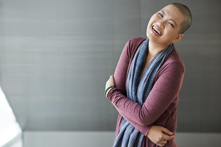 Laughing Asian woman with shaved head looking at cameraの写真素材