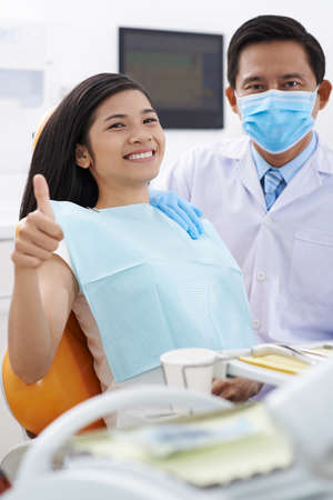 Happy Vietnamese girl showing thumbs-up after dental check-upの写真素材