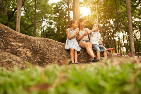 Happy children enjoying ice cream cones in the parkの写真素材