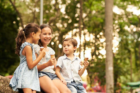 Indonesian children talking and eating ice cream in the parkの写真素材