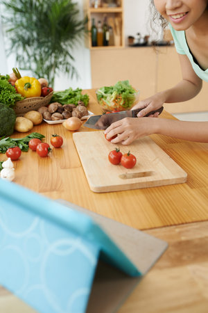 Smiling girl cutting tomatoes on the cutting board