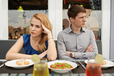 Unhappy young couple sitting in the restaurant