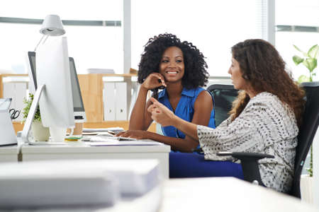 Business lady explaining her ideas to smiling colleagueの写真素材