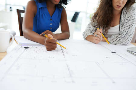 Female engineer and project manager discussing blueprintの写真素材