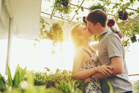 Beautiful couple kissing in green-houseの写真素材