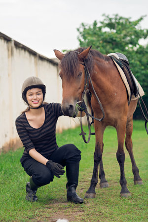 Lovely teenaged girl posing with horse after trainingの写真素材