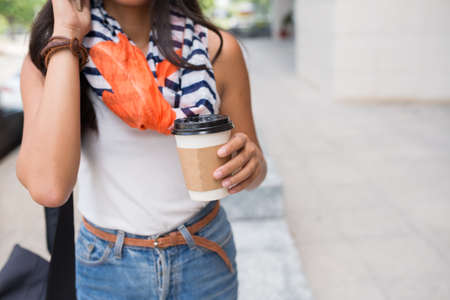 Cropped image of woman with take-out coffee talking on the phoneの写真素材