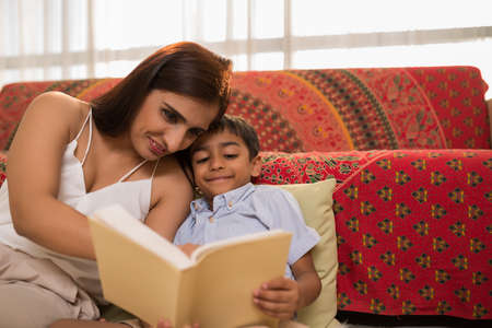 Pretty Indian woman teaching her little son readingの写真素材
