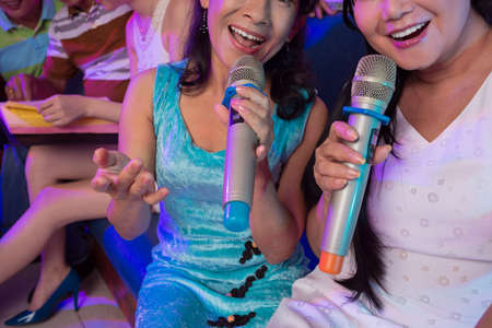 Cropped image of two women singing in microphonesの写真素材