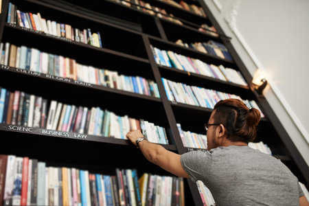 Man looking for a book on a shelf in library