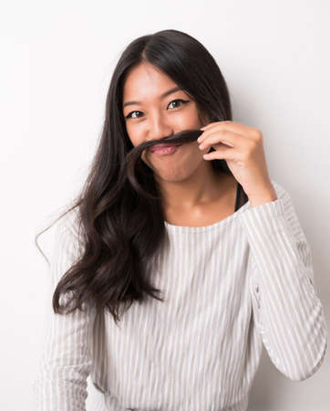 Funny young woman making moustache out of her hairの写真素材