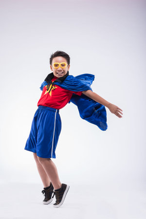 Cheerful boy wearing superhero costume with a capeの写真素材