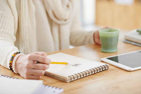 Close-up image of woman drawing portrait in notepad