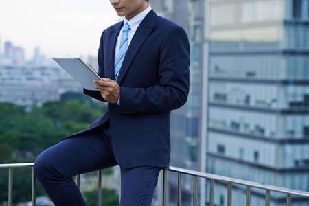 Young business executive working on digital tablet when standing rooftop of skyscraperの写真素材