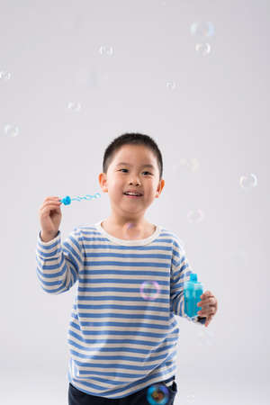 Portrait of excited kid blowing bubbles, isolated on greyの写真素材