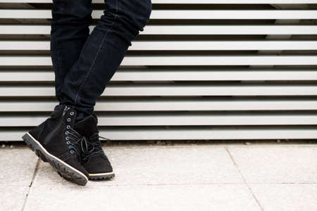 Legs of man in black suede boots standing at the wallの写真素材